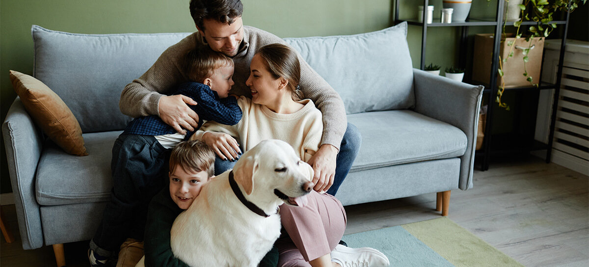 Family embracing with dog in their home.